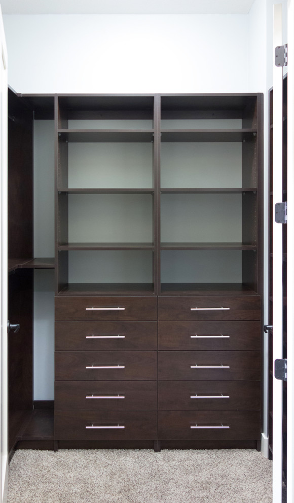 Mid-sized transitional gender-neutral walk-in wardrobe in Vancouver with flat-panel cabinets, dark wood cabinets and carpet.