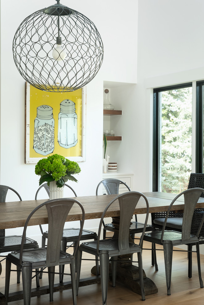 This is an example of a country open plan dining in Denver with white walls and light hardwood floors.
