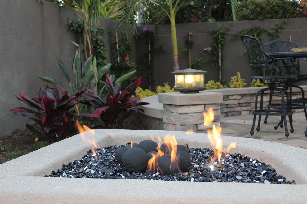 Photo of a mid-sized mediterranean backyard partial sun xeriscape for summer in Orange County with a fire feature and natural stone pavers.