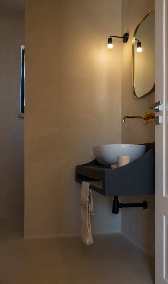 Exemple d'une salle de bain méditerranéenne avec des portes de placard noires, une douche à l'italienne, WC séparés, un mur beige, un sol en terrazzo, une vasque, un plan de toilette en acier inoxydable, un sol beige, aucune cabine, meuble simple vasque et meuble-lavabo suspendu.
