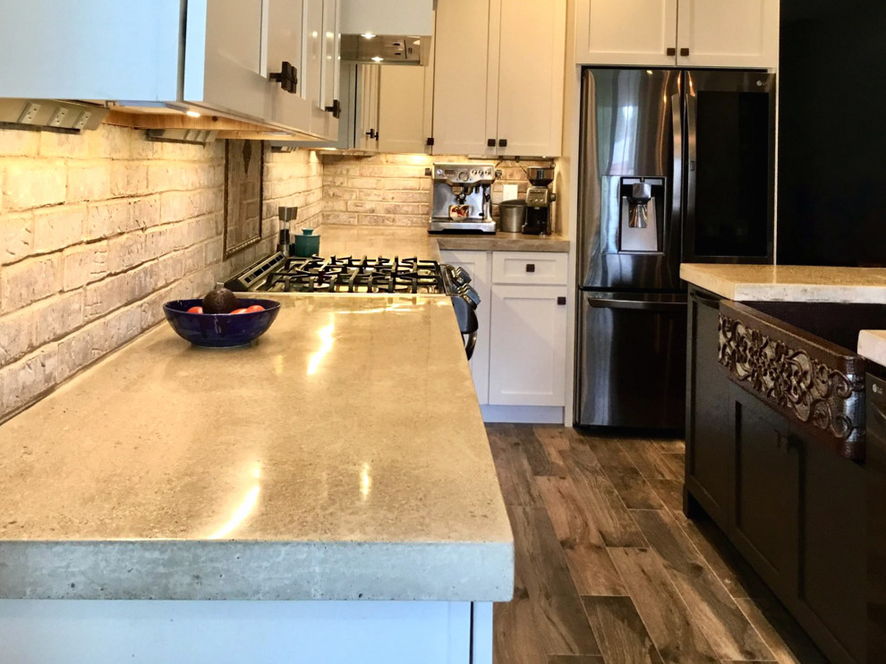 Example of a mid-sized cottage l-shaped ceramic tile and brown floor eat-in kitchen design in Columbus with a farmhouse sink, shaker cabinets, white cabinets, concrete countertops and an island