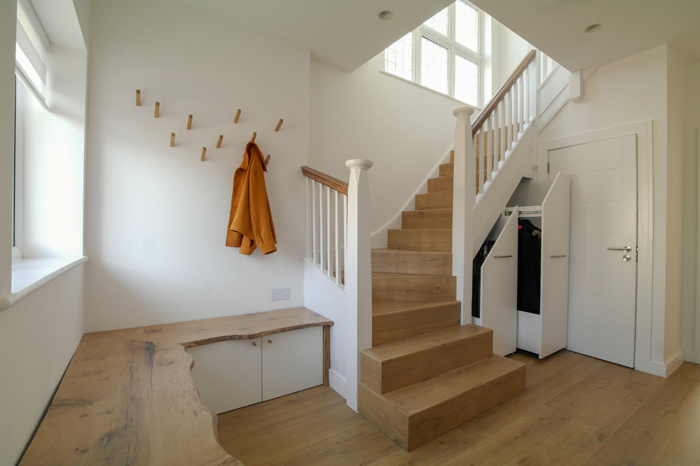 Photo of a transitional wood u-shaped staircase in London with wood risers and wood railing.
