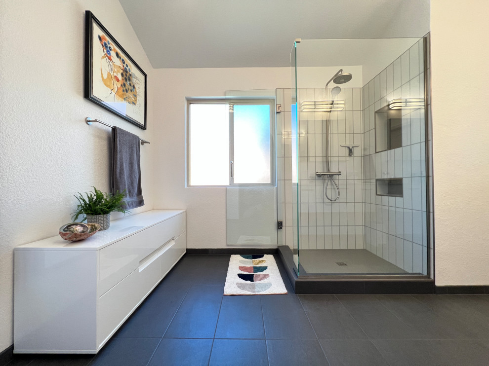 Пример оригинального дизайна: большая главная ванная комната в стиле неоклассика (современная классика) с плоскими фасадами, белыми фасадами, душем в нише, белой плиткой, керамогранитной плиткой, белыми стенами, полом из керамогранита, черным полом, душем с распашными дверями, белой столешницей, нишей и встроенной тумбой