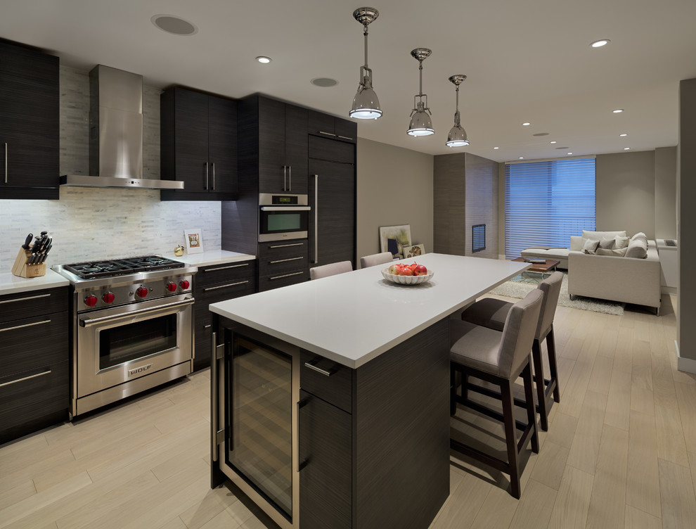 Design ideas for a mid-sized contemporary l-shaped open plan kitchen in New York with flat-panel cabinets, dark wood cabinets, quartz benchtops, grey splashback, stainless steel appliances, light hardwood floors, with island, stone tile splashback and an undermount sink.