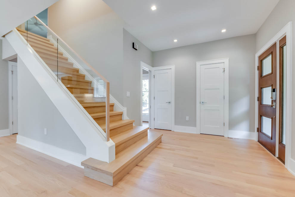Photo of a mid-sized transitional wood straight staircase in DC Metro with wood risers and glass railing.