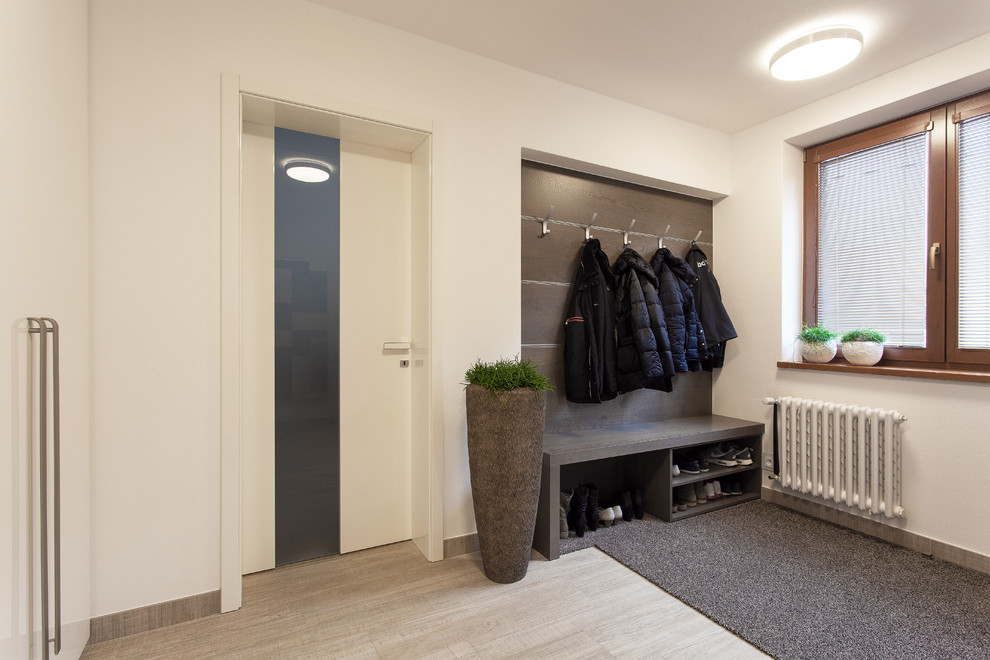 This is an example of a mid-sized contemporary vestibule in Other with white walls and medium hardwood floors.