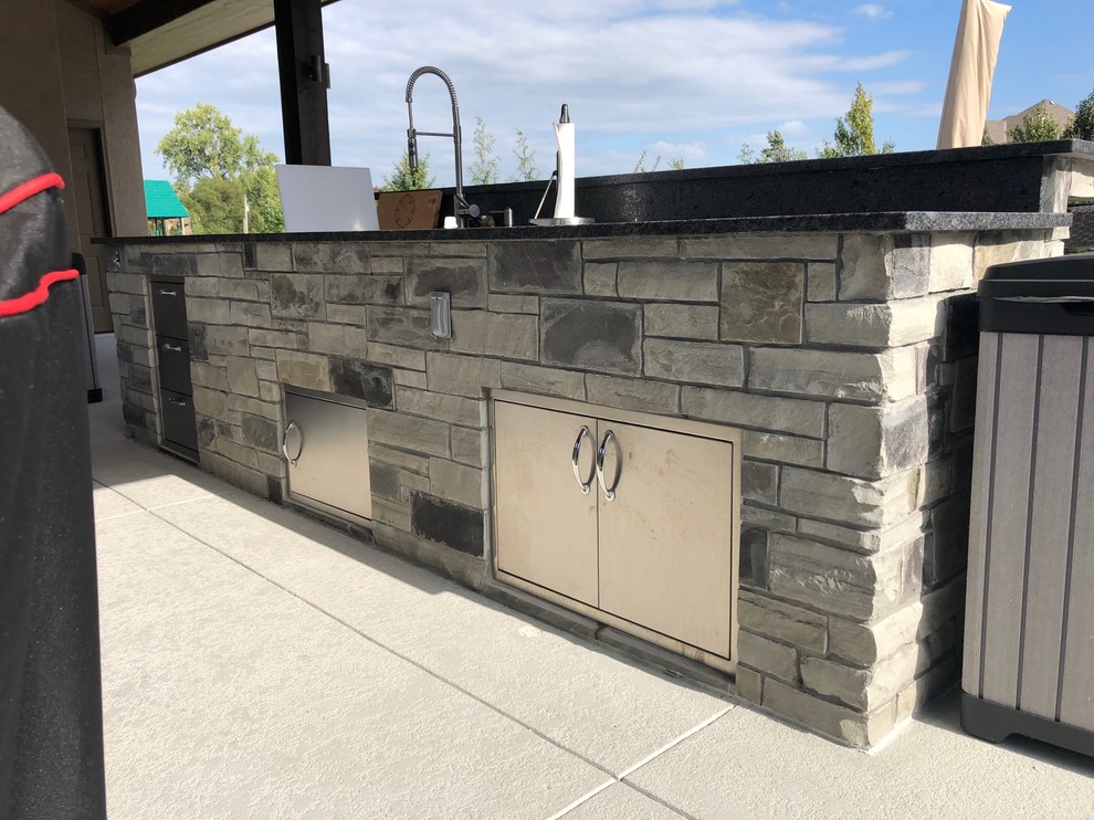 Inspiration for a modern backyard patio in Other with an outdoor kitchen, stamped concrete and a roof extension.