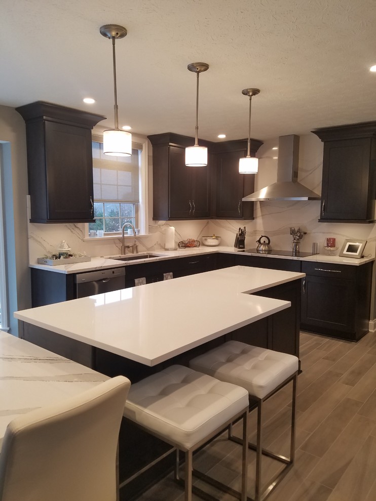 Enclosed kitchen - mid-sized transitional l-shaped porcelain tile and gray floor enclosed kitchen idea with an undermount sink, raised-panel cabinets, dark wood cabinets, quartz countertops, white backsplash, stone slab backsplash, stainless steel appliances and an island
