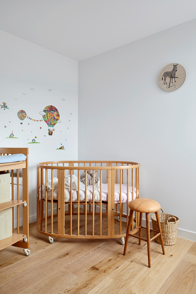 Design ideas for a small contemporary gender-neutral nursery in Melbourne with white walls, light hardwood floors and beige floor.