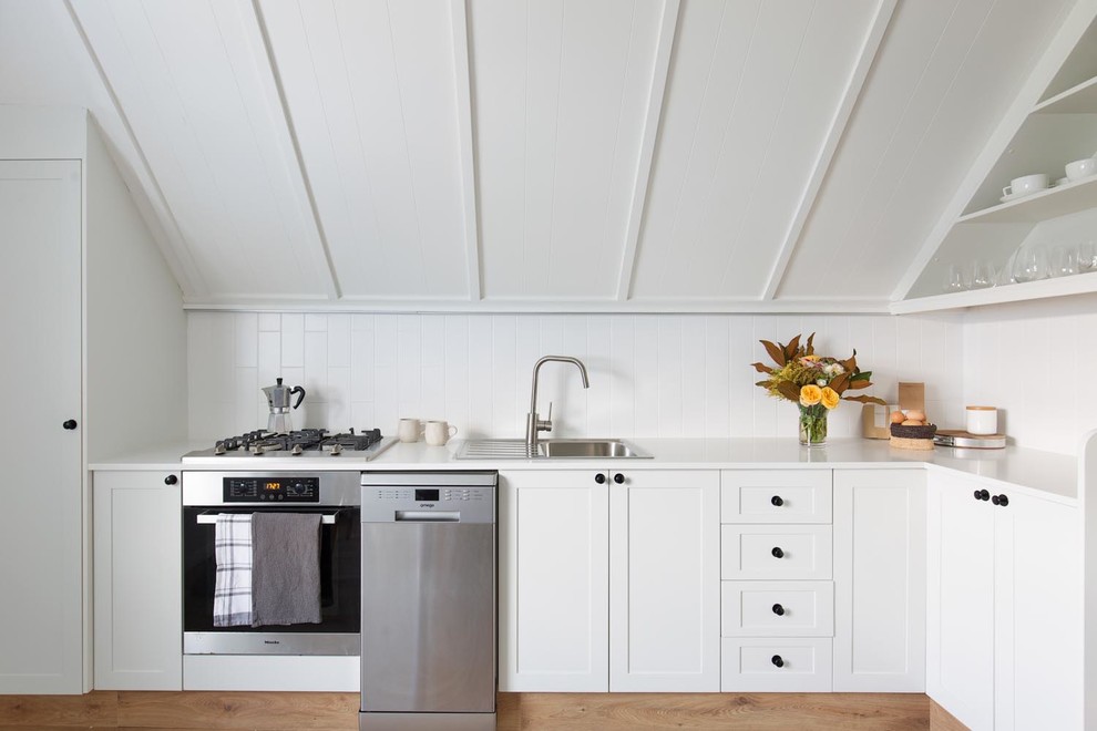 Design ideas for a mid-sized country l-shaped kitchen in Wollongong with white cabinets, quartz benchtops, white splashback, ceramic splashback, stainless steel appliances, white benchtop, a drop-in sink, shaker cabinets and no island.