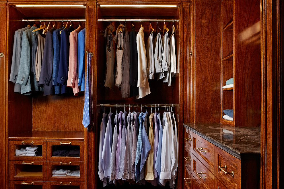 Design ideas for a mediterranean men's built-in wardrobe in Other with recessed-panel cabinets and dark wood cabinets.