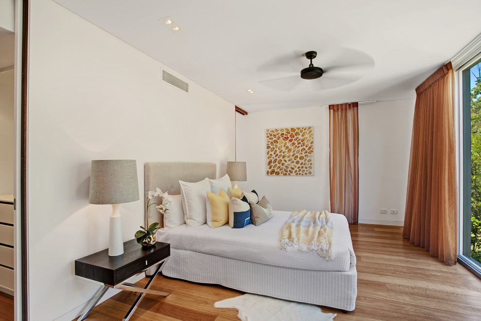 Photo of a mid-sized contemporary master bedroom in Sunshine Coast with white walls and medium hardwood floors.