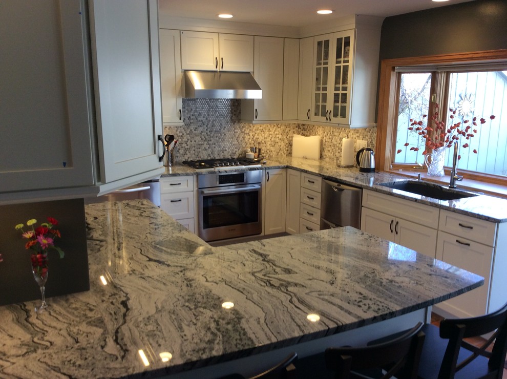 Mid-sized transitional l-shaped medium tone wood floor kitchen pantry photo in Denver with an undermount sink, shaker cabinets, white cabinets, granite countertops, gray backsplash, ceramic backsplash and stainless steel appliances