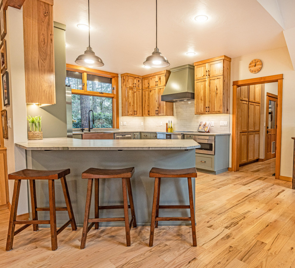 Inspiration for a large rustic u-shaped light wood floor and brown floor eat-in kitchen remodel with a farmhouse sink, shaker cabinets, quartzite countertops, gray backsplash, ceramic backsplash, stainless steel appliances, a peninsula and gray countertops
