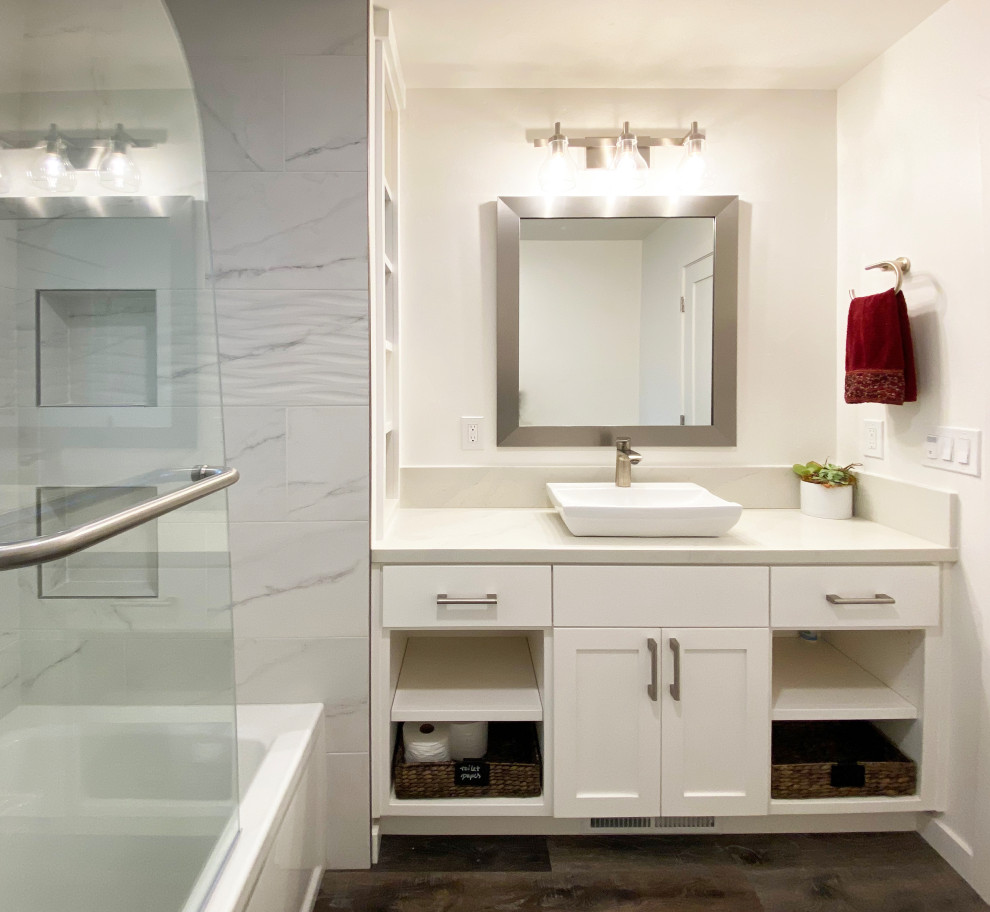 Alcove bathtub - mid-sized transitional 3/4 black and white tile and porcelain tile vinyl floor, brown floor and single-sink alcove bathtub idea with shaker cabinets, white cabinets, a two-piece toilet, white walls, a vessel sink, quartz countertops, a hinged shower door, gray countertops, a niche and a built-in vanity