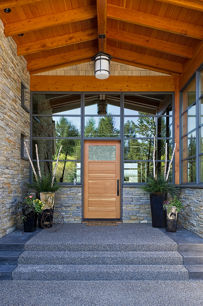 Photo of a contemporary front door in Calgary with a single front door, brown walls, carpet, a medium wood front door and grey floor.