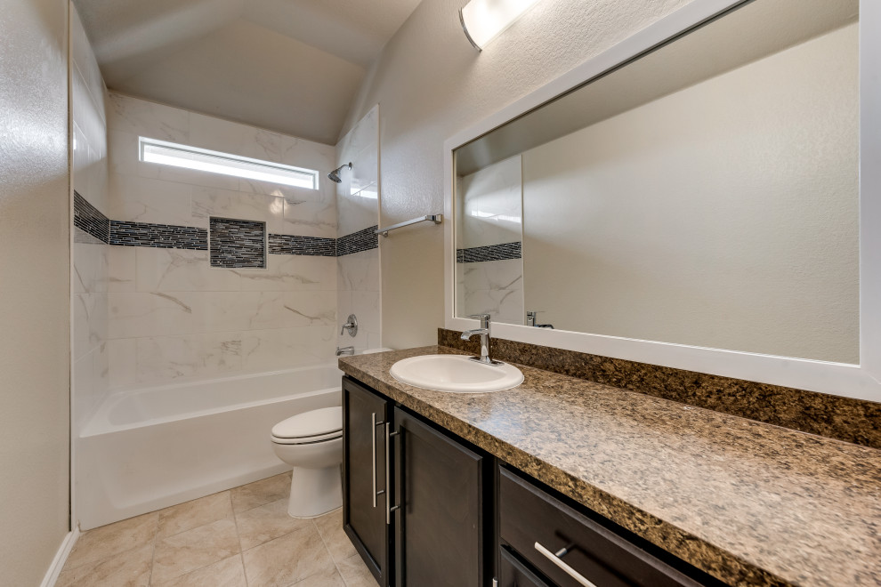 This is an example of a mid-sized traditional master bathroom in Houston with raised-panel cabinets, brown cabinets, a corner tub, a one-piece toilet, beige tile, ceramic tile, beige walls, porcelain floors, a drop-in sink, quartzite benchtops, brown floor, brown benchtops, a double vanity, a built-in vanity, coffered and decorative wall panelling.