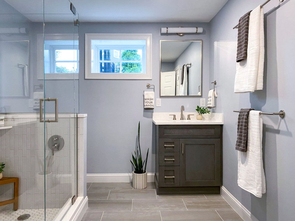 Corner shower - transitional white tile and ceramic tile porcelain tile, gray floor and single-sink corner shower idea in Boston with shaker cabinets, gray cabinets, a one-piece toilet, gray walls, an undermount sink, quartz countertops, a hinged shower door, white countertops and a built-in vanity