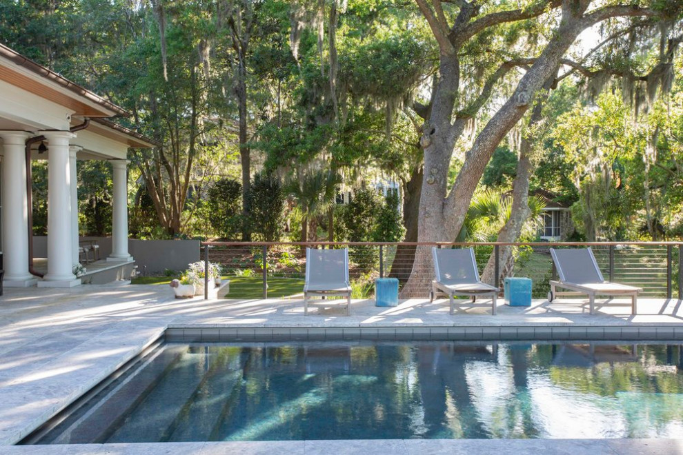 Large beach style backyard rectangular infinity pool in Charleston with concrete pavers.