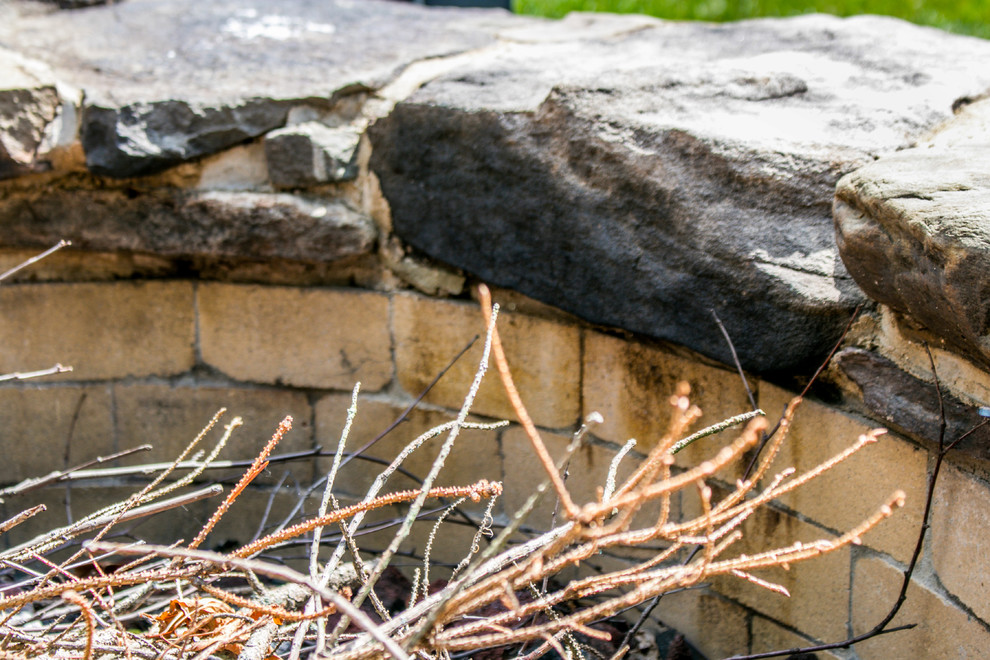 Design ideas for a rustic backyard stone landscaping in Chicago with a fire pit.