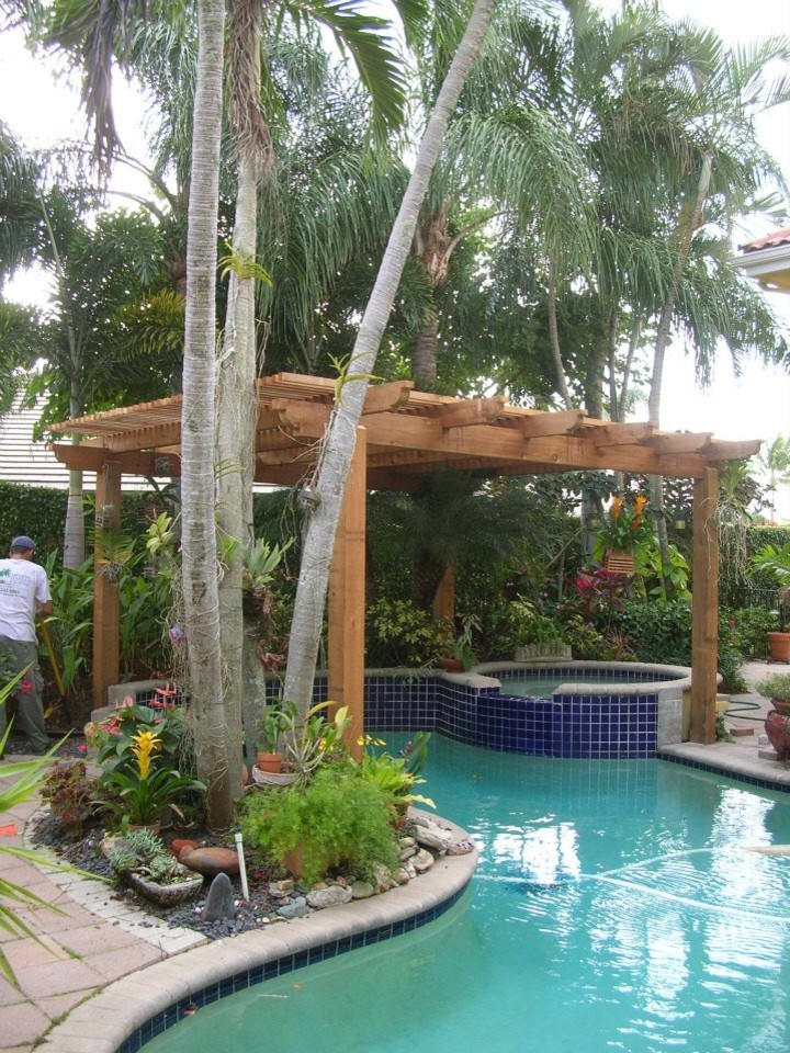 Mid-sized tropical backyard custom-shaped pool in Miami with a water feature and natural stone pavers.