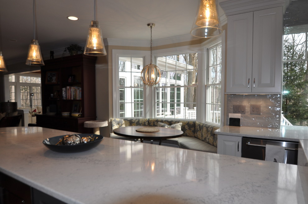 Photo of a mid-sized transitional l-shaped open plan kitchen in Boston with an undermount sink, raised-panel cabinets, white cabinets, quartz benchtops, grey splashback, porcelain splashback, stainless steel appliances, medium hardwood floors, with island, brown floor and white benchtop.