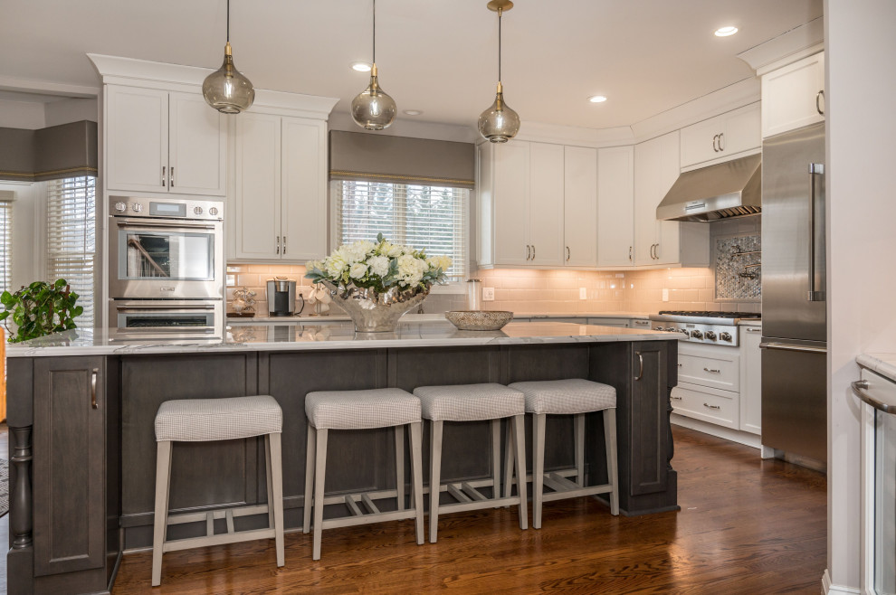 Transitional l-shaped dark wood floor and brown floor kitchen photo in DC Metro with shaker cabinets, white cabinets, beige backsplash, subway tile backsplash, stainless steel appliances, an island and gray countertops