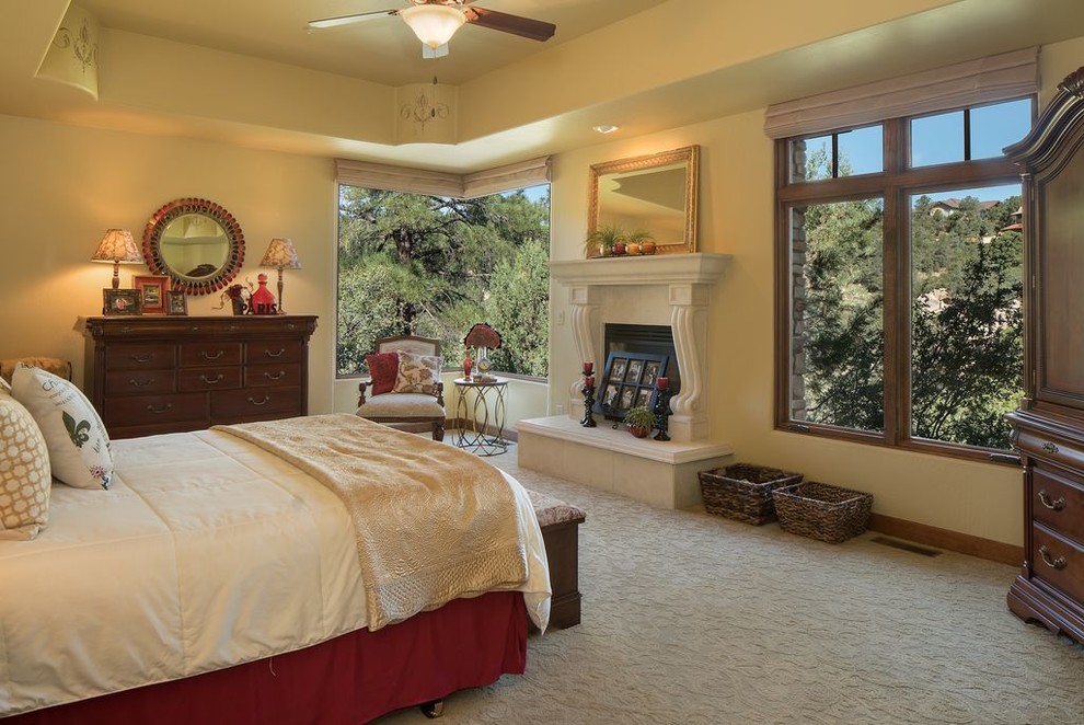 This is an example of a large traditional guest bedroom in Phoenix with beige walls, carpet, a standard fireplace and a plaster fireplace surround.