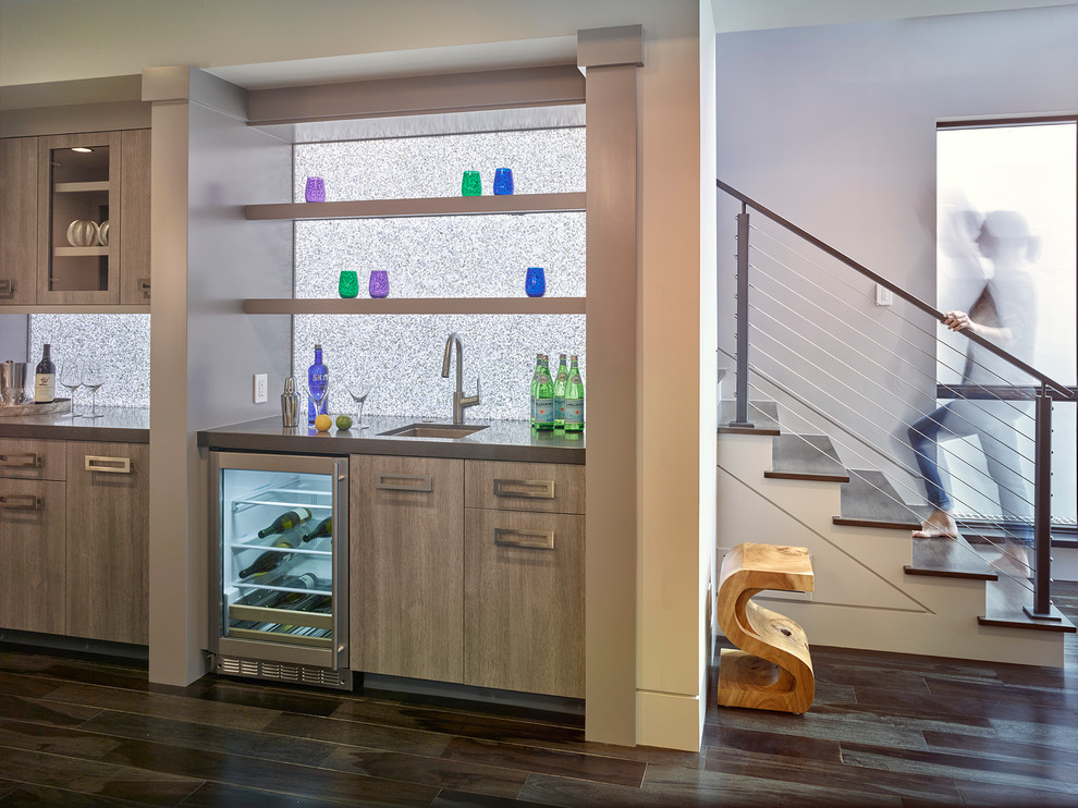 This is an example of a small contemporary single-wall wet bar in San Francisco with an undermount sink, flat-panel cabinets, light wood cabinets, quartz benchtops, grey splashback, glass sheet splashback and dark hardwood floors.