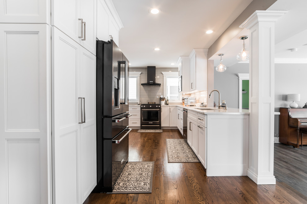 Example of a mid-sized transitional l-shaped medium tone wood floor and brown floor eat-in kitchen design in Chicago with an undermount sink, recessed-panel cabinets, white cabinets, quartzite countertops, gray backsplash, subway tile backsplash, black appliances, no island and multicolored countertops