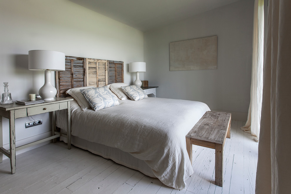 This is an example of a mid-sized country master bedroom in Madrid with white walls, painted wood floors and no fireplace.