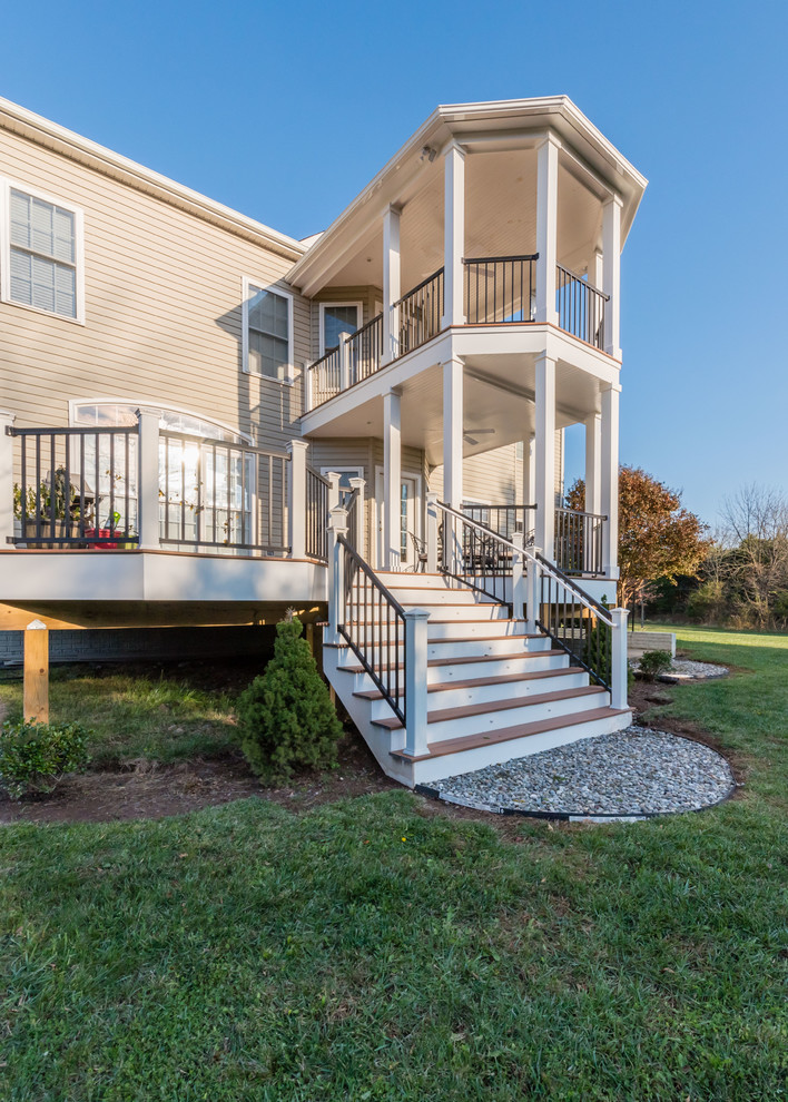 Example of a large transitional backyard deck design with decking and a roof extension