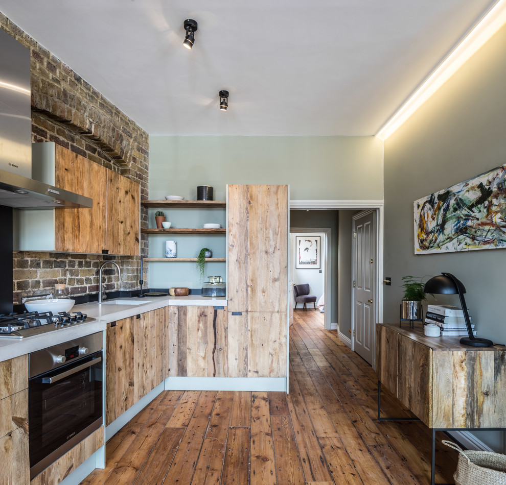 Photo of a small modern l-shaped open plan kitchen in London with flat-panel cabinets, medium wood cabinets, concrete benchtops, brown splashback, brick splashback, panelled appliances, medium hardwood floors and no island.