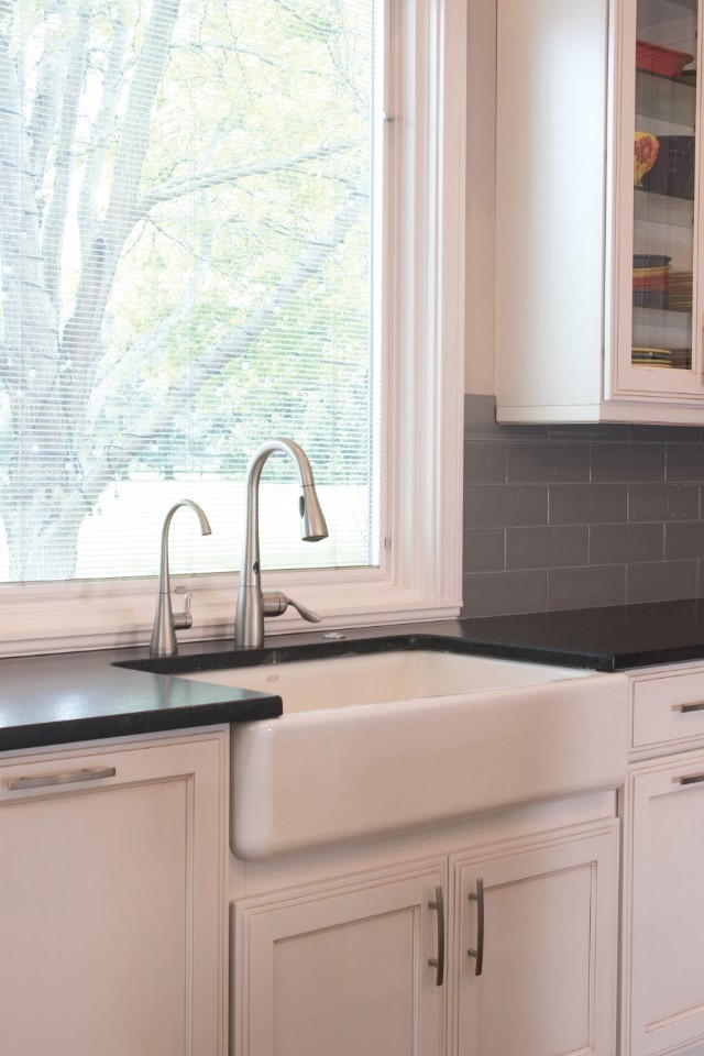Large transitional l-shaped medium tone wood floor eat-in kitchen photo in Cincinnati with a farmhouse sink, recessed-panel cabinets, white cabinets, granite countertops, gray backsplash, ceramic backsplash, an island and paneled appliances