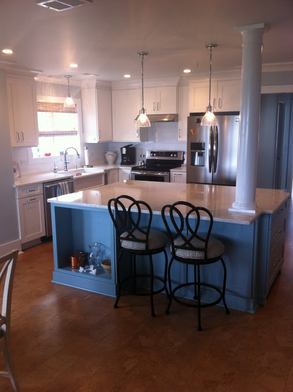 Kitchen - cork floor kitchen idea with a farmhouse sink, marble countertops, white backsplash, subway tile backsplash, stainless steel appliances and an island