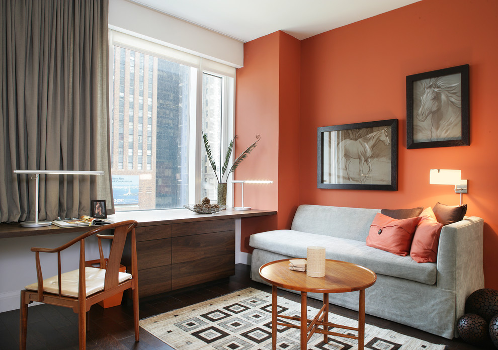 This is an example of a contemporary home office in New York with orange walls and a built-in desk.