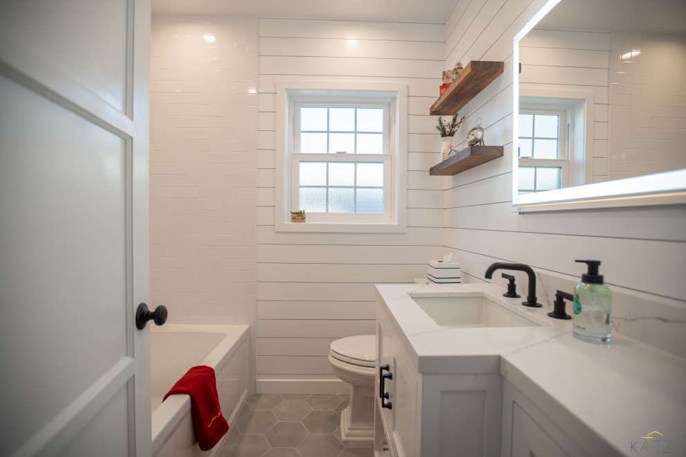 Diseño de cuarto de baño único y a medida de tamaño medio con bañera encastrada, combinación de ducha y bañera, sanitario de una pieza, baldosas y/o azulejos blancos, paredes blancas, encimera de mármol, suelo gris, ducha con cortina y encimeras blancas