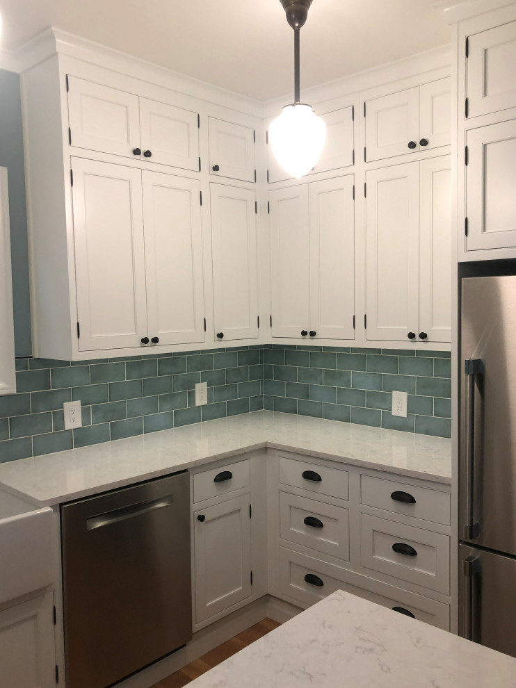 Example of a mid-sized classic u-shaped eat-in kitchen design in Seattle with a farmhouse sink, shaker cabinets, white cabinets, quartz countertops, a peninsula and white countertops