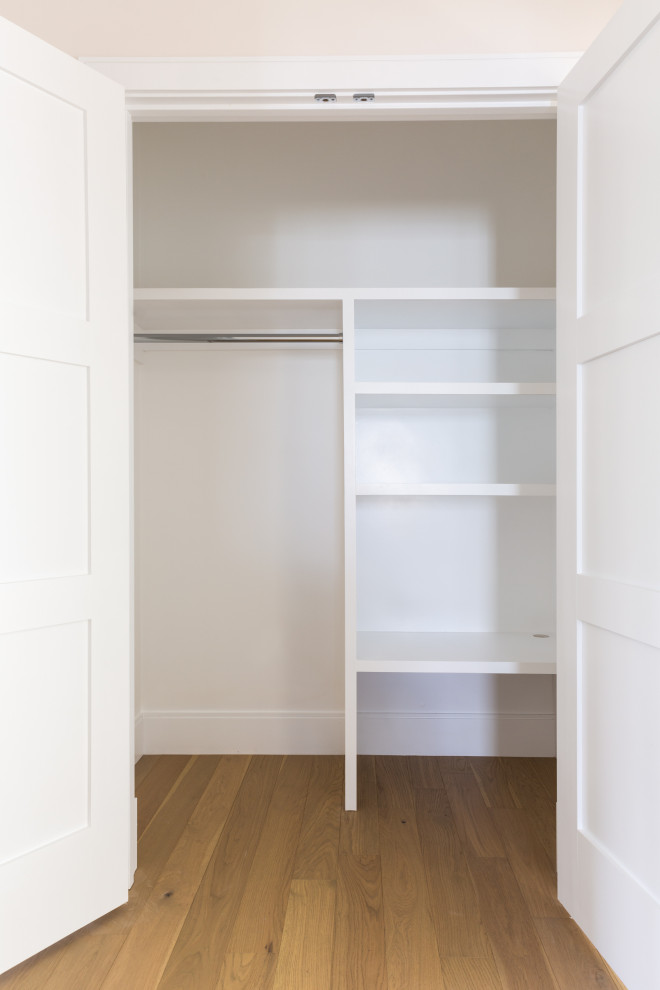 Example of a mid-sized transitional gender-neutral light wood floor and beige floor reach-in closet design in Boston