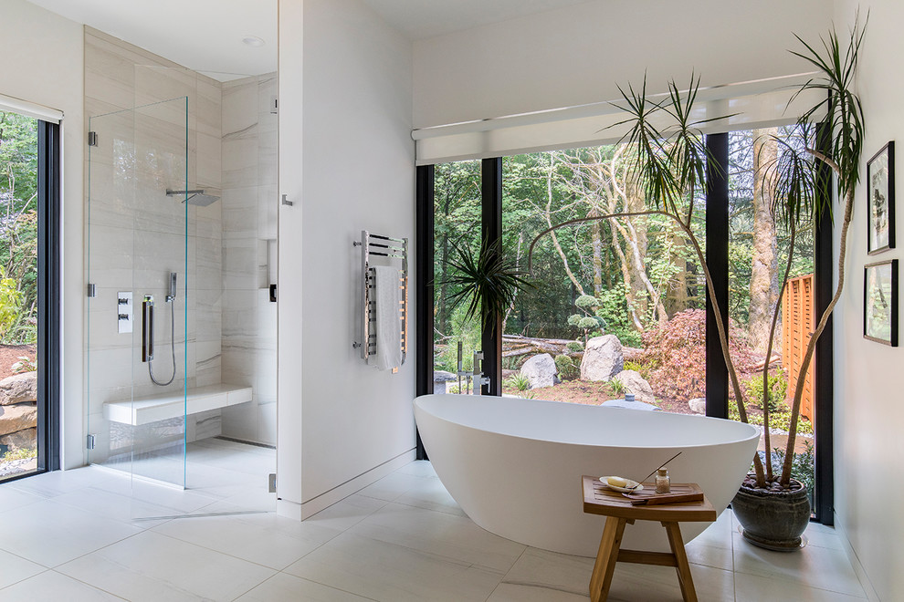 Photo of a contemporary master bathroom in Portland with a freestanding tub, a curbless shower, gray tile, white walls, white floor and a hinged shower door.