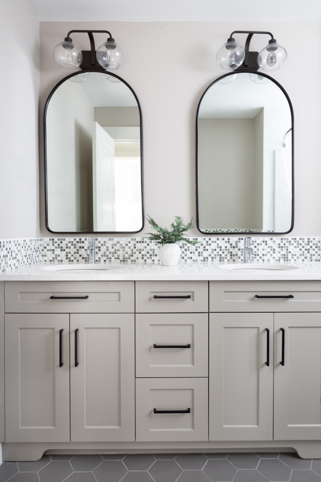 Foto de cuarto de baño infantil, doble y a medida tradicional renovado con armarios estilo shaker, puertas de armario beige, bañera empotrada, combinación de ducha y bañera, baldosas y/o azulejos grises, baldosas y/o azulejos de vidrio, paredes blancas, suelo de madera clara, lavabo bajoencimera, encimera de acrílico, suelo beige y encimeras blancas