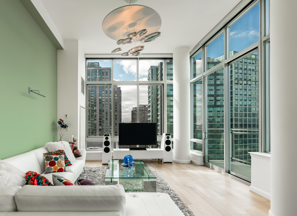 Example of a huge trendy enclosed light wood floor and beige floor living room design in New York with green walls and a tv stand