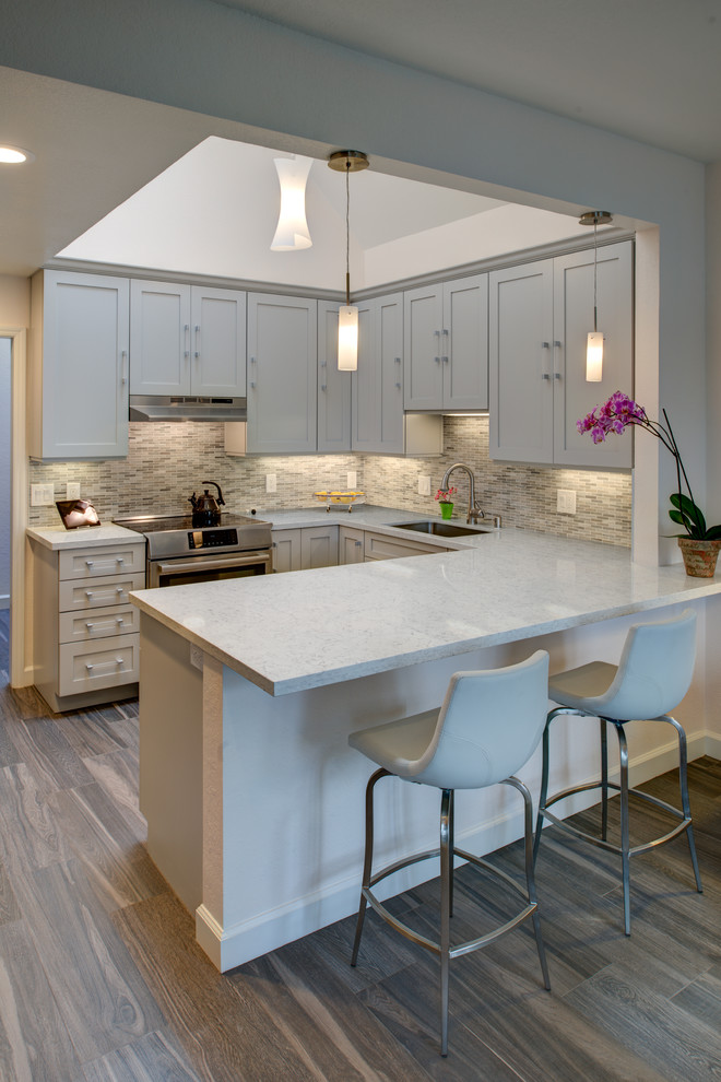 Design ideas for a mid-sized transitional u-shaped kitchen in San Francisco with an undermount sink, shaker cabinets, grey cabinets, quartz benchtops, stainless steel appliances, dark hardwood floors and a peninsula.