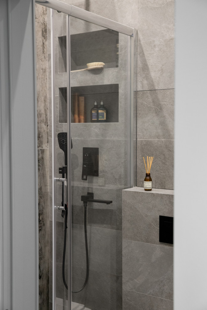 Пример оригинального дизайна: серо-белая ванная комната среднего размера в скандинавском стиле с плоскими фасадами, белыми фасадами, душем в нише, инсталляцией, серой плиткой, керамогранитной плиткой, серыми стенами, полом из керамогранита, душевой кабиной, серым полом, душем с раздвижными дверями, зеркалом с подсветкой, тумбой под одну раковину и подвесной тумбой