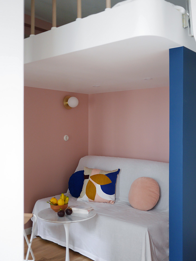 Modelo de salón abierto moderno pequeño con paredes rosas, suelo de madera clara y suelo beige