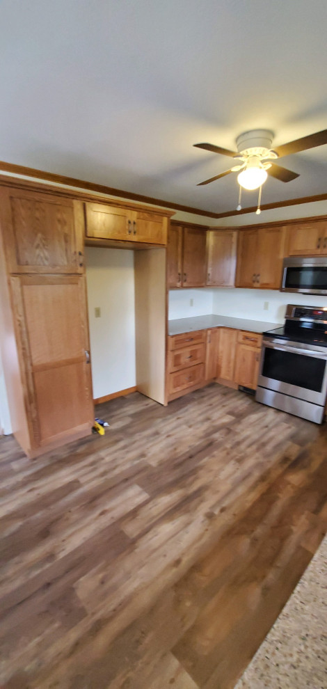 Mid-sized elegant u-shaped vinyl floor and brown floor eat-in kitchen photo with an undermount sink, shaker cabinets, medium tone wood cabinets, quartz countertops, stainless steel appliances, no island and beige countertops