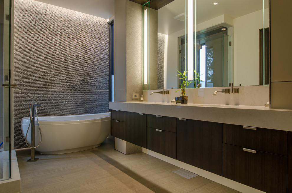 Photo of a mid-sized contemporary master bathroom in Seattle with flat-panel cabinets, dark wood cabinets, a freestanding tub, beige tile, stone tile, multi-coloured walls, porcelain floors, an undermount sink, limestone benchtops and beige floor.