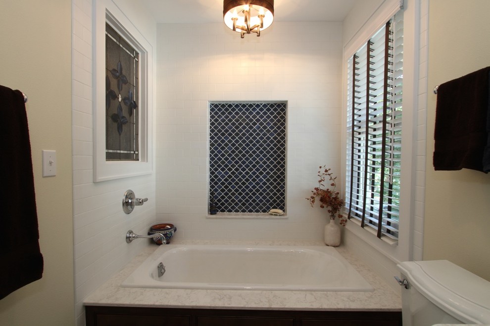 Photo of a large mediterranean master bathroom in Milwaukee with furniture-like cabinets, dark wood cabinets, a drop-in tub, a two-piece toilet, white tile, subway tile, beige walls, cement tiles, an undermount sink, engineered quartz benchtops, a hinged shower door, an alcove shower and blue floor.