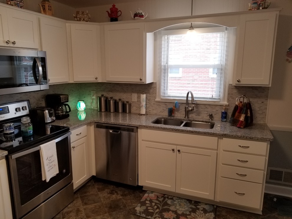 Example of a small transitional l-shaped vinyl floor and gray floor eat-in kitchen design with a double-bowl sink, shaker cabinets, white cabinets, granite countertops, gray backsplash, mosaic tile backsplash, stainless steel appliances, no island and multicolored countertops