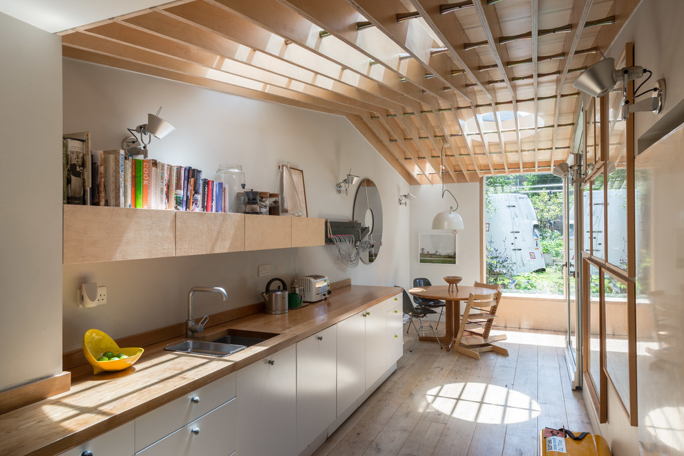 Mid-sized scandinavian single-wall eat-in kitchen in Oxfordshire with flat-panel cabinets, white cabinets, wood benchtops, light hardwood floors, an undermount sink, beige floor and beige benchtop.